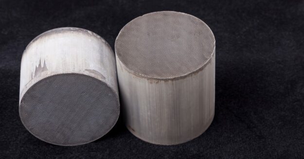 Two metal catalysts used in chemistry. They are cylindrical in shape and have a distinct pattern on the flat surface.