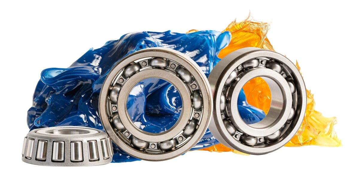 Stainless steel ball bearings in front of blue and orange lithium grease, against a white background. Stainless steel ball bearings in front of blue and orange lithium grease, against a white background.