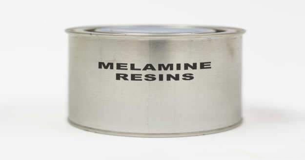 A metal container labeled "Melamine Resins" in black letters. The container sits against a plain white background.