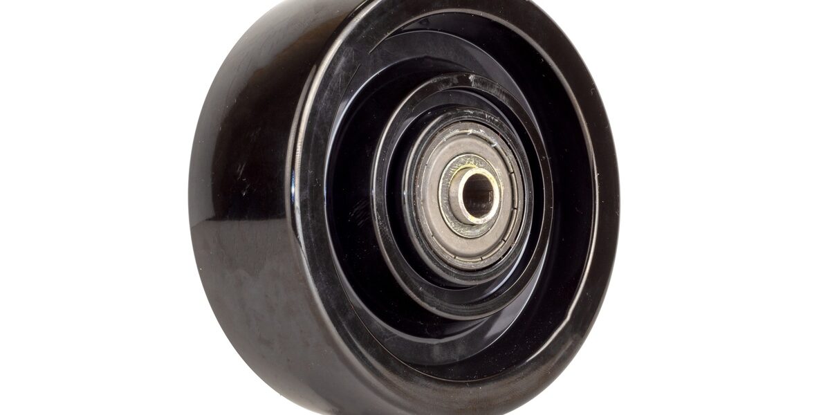 A single black phenolic resin caster wheel against a white background. Light reflects off its smooth surface.