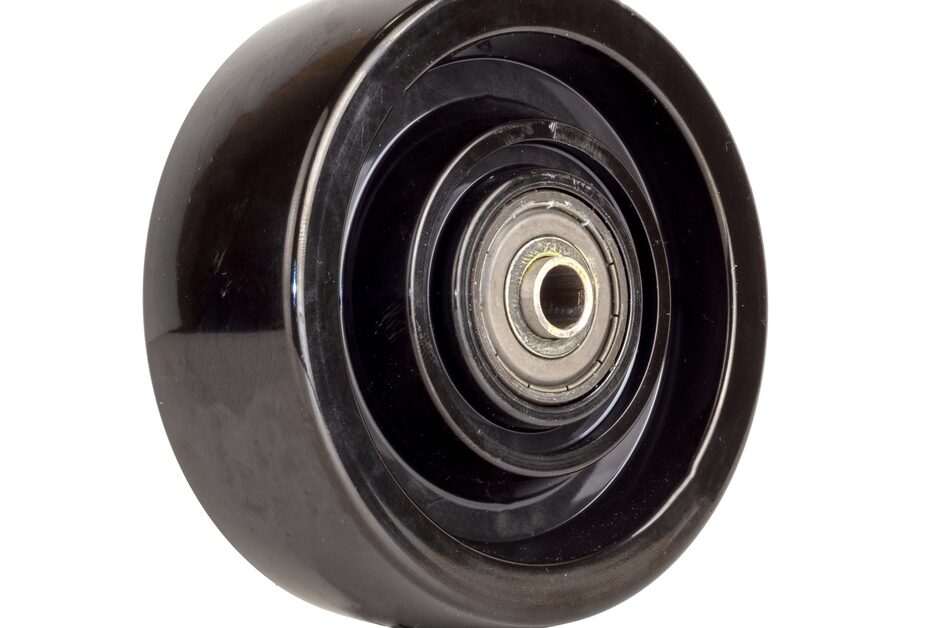A single black phenolic resin caster wheel against a white background. Light reflects off its smooth surface.