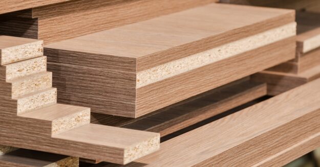 Multiple stacks of cut medium-density fiberboard (MDF) panels in different sizes, with finished and unfinished edges.