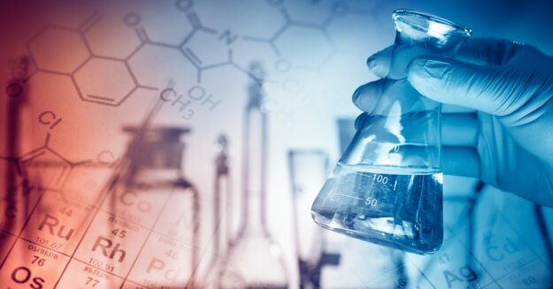 A gloved hand holds a laboratory flask with clear liquid against a lab background with chemical formulas and equipment.