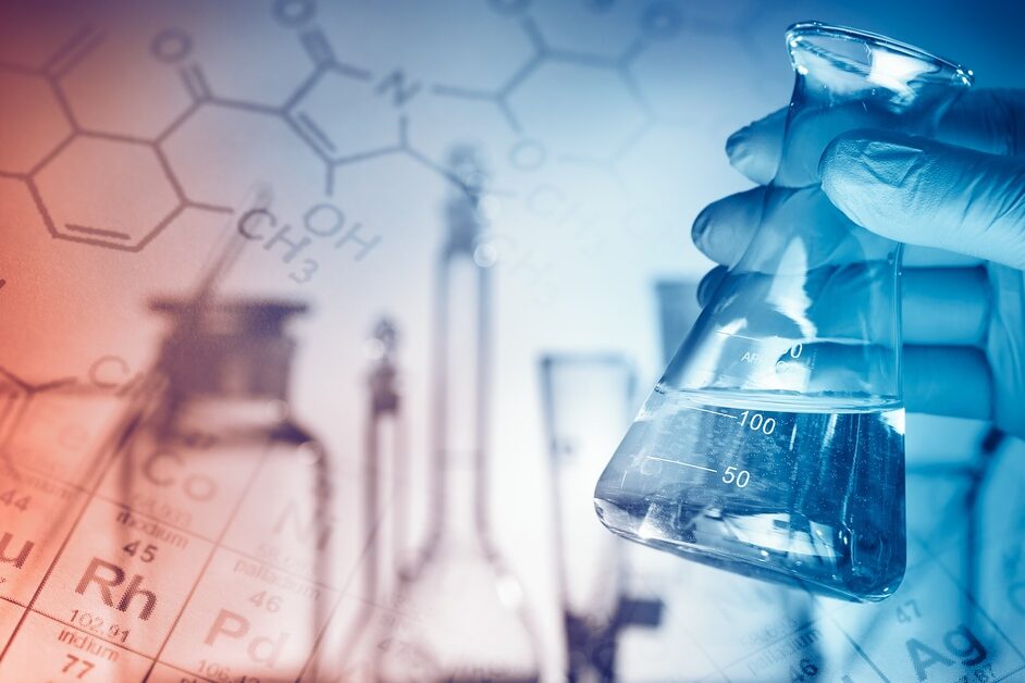 A gloved hand holds a laboratory flask with clear liquid against a lab background with chemical formulas and equipment.