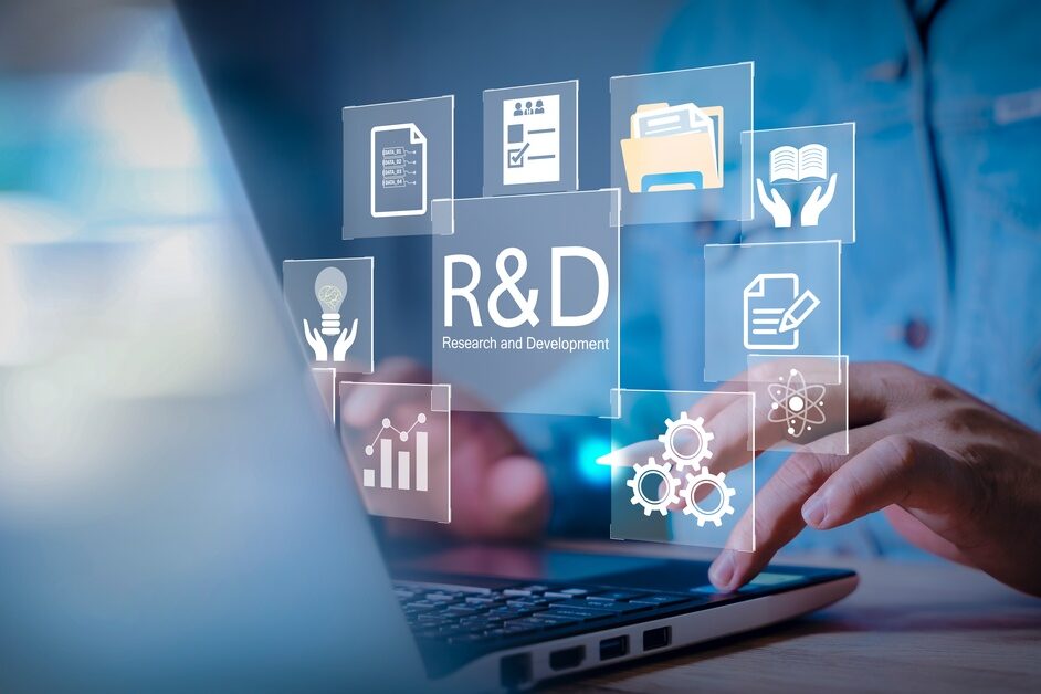A man is sitting at a desk and typing on a laptop. There are graphics floating between the man and his laptop screen.