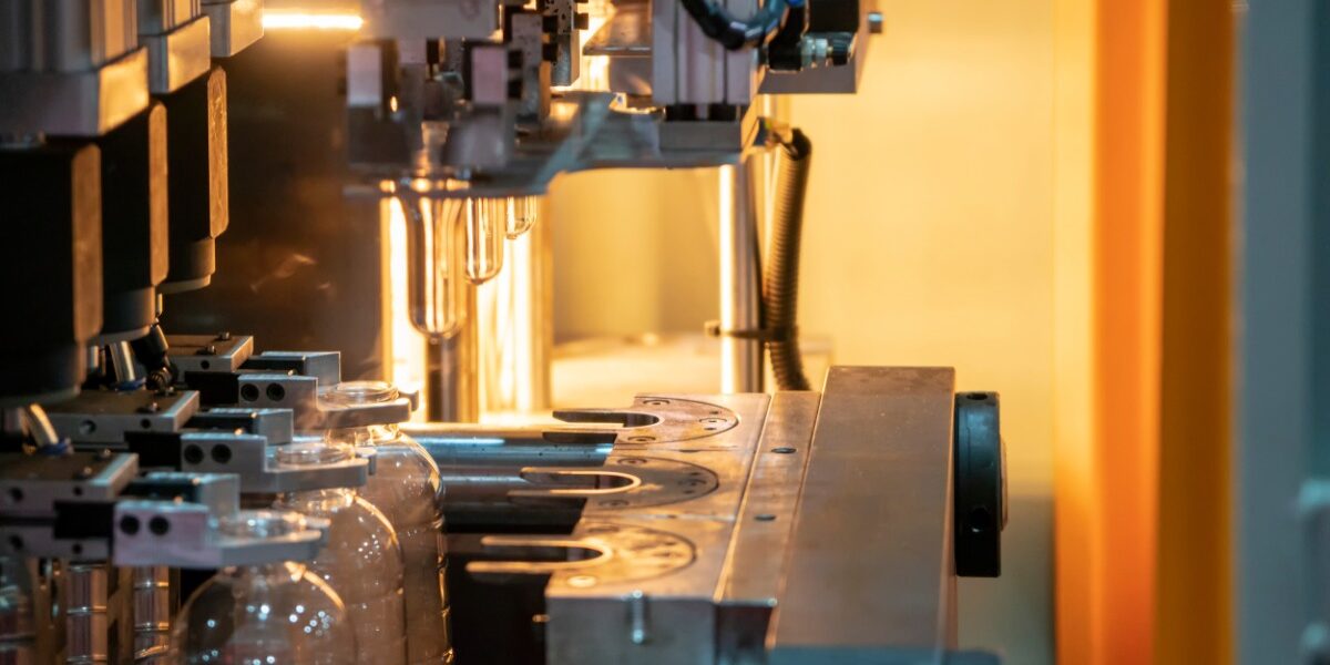 Several plastic bottles are in a machine. There is an orange light behind the machine, bouncing off the back wall.