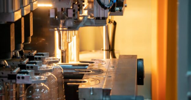Several plastic bottles are in a machine. There is an orange light behind the machine, bouncing off the back wall.