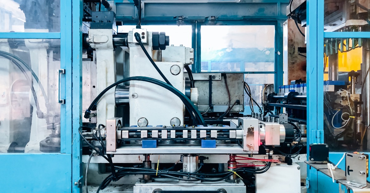 An industrial machine is installed in front of a window. The machine is silver and it is next to a wall with blue trim.