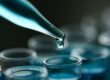 A dropper is dropping a blue liquid into a clear test tube that already has blue liquid in it.