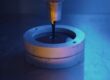 Resin is being poured into a mold. The mold is in an industrial setting and there is a dark blue light.