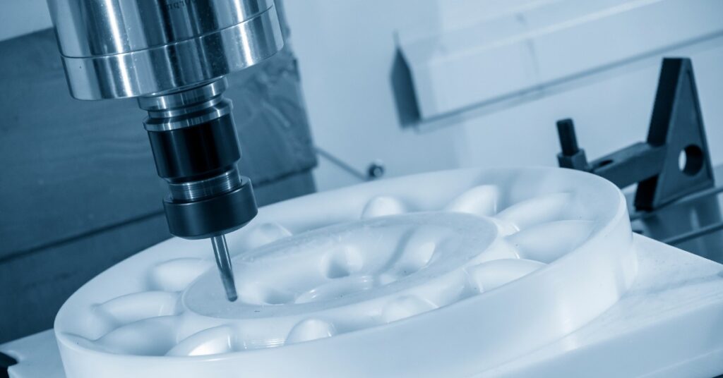 A machine is working on a white substance. The white piece of material has groves in it.